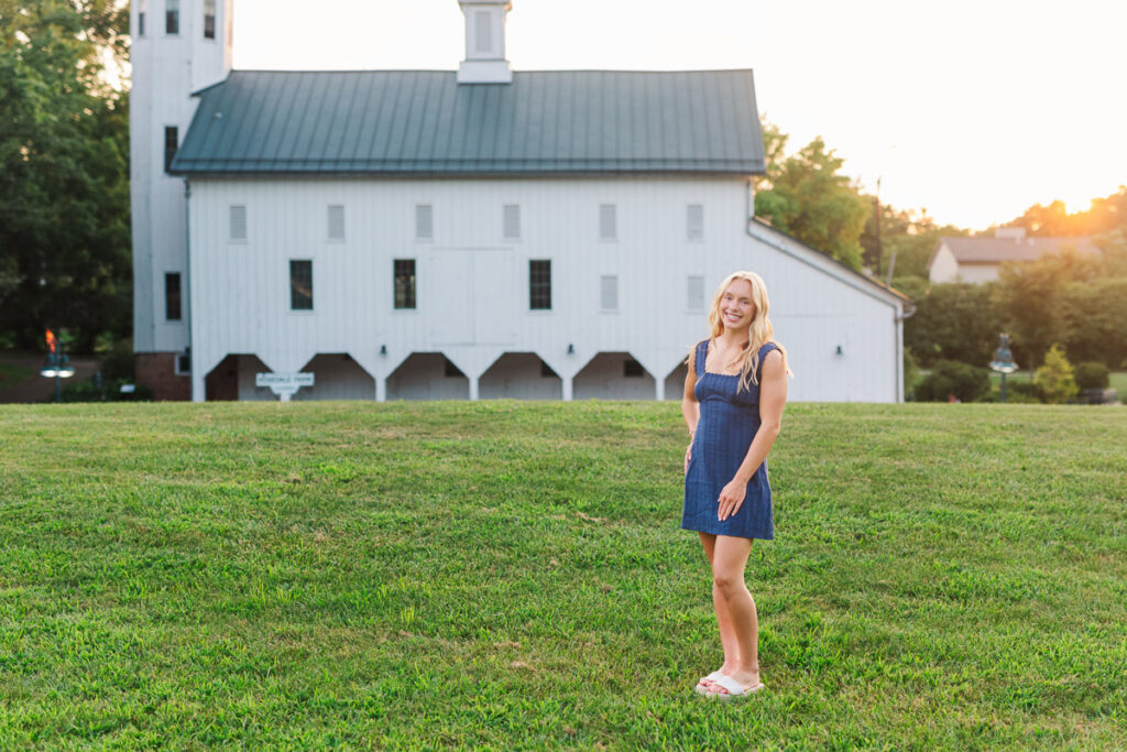 a senior girl posing in front of a white barn for her senior session