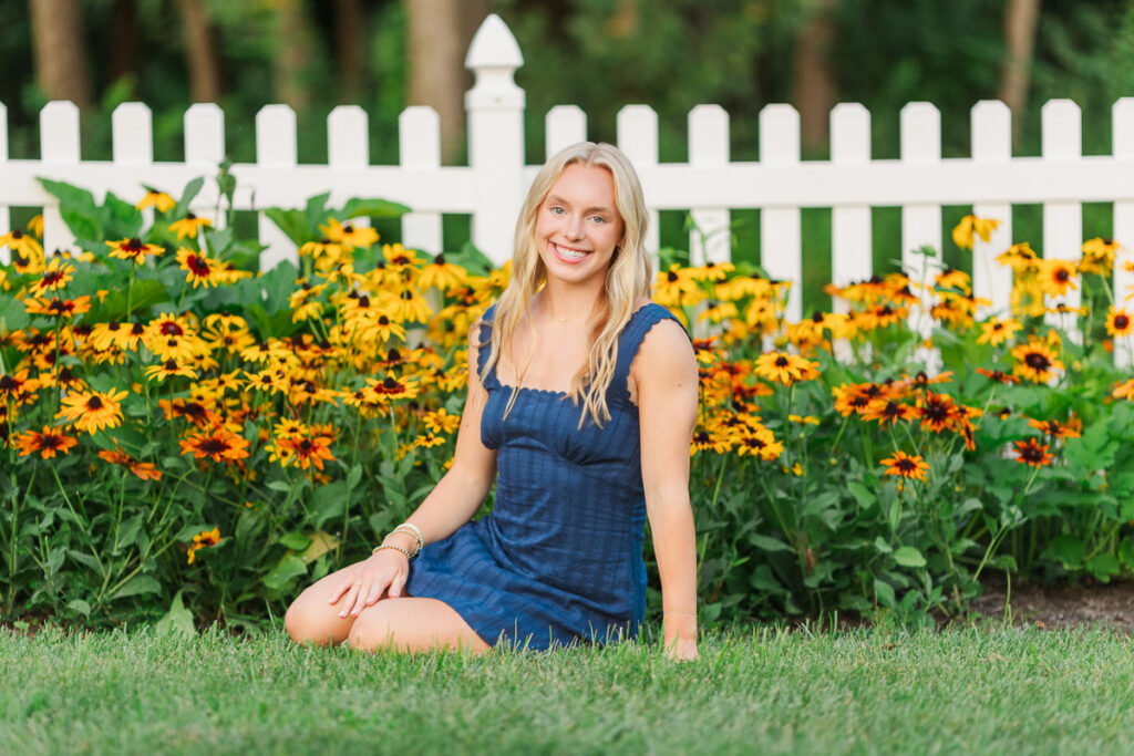 a senior girl sitting in front of flowers for her senior session