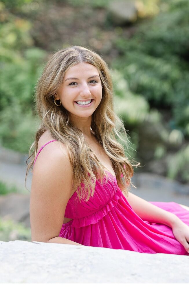 high school senior wearing pink dress sitting on stairs
