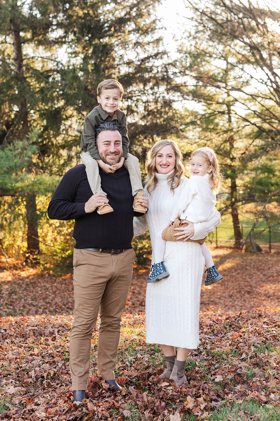 A family with the dad holding son on his shoulders and mom holding daughter during a mini session
