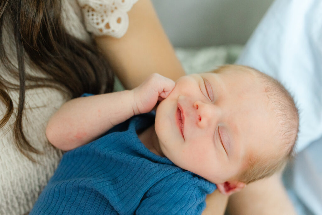 a baby boy smiling as his mom holds him.