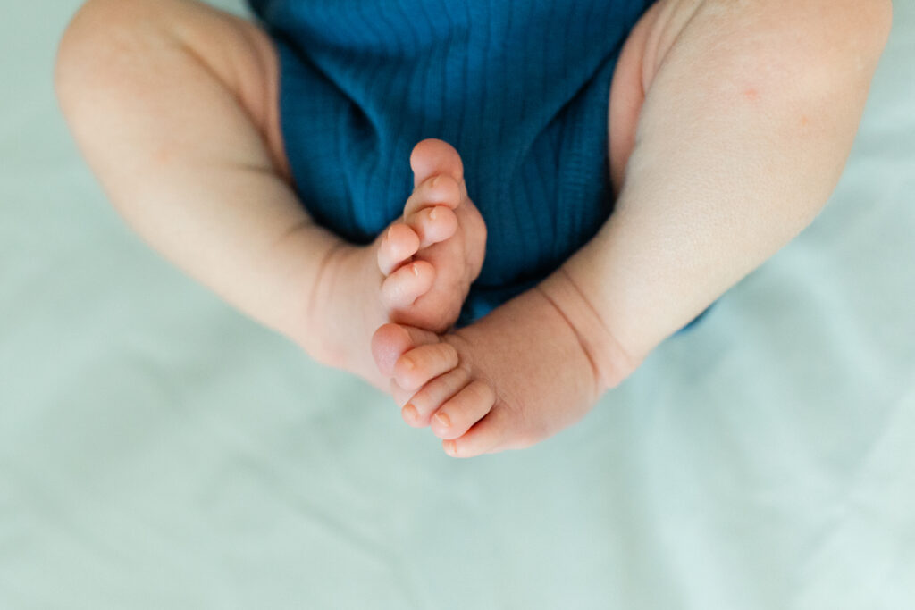 a baby curling his feet on a bed showing off his adorable toes
