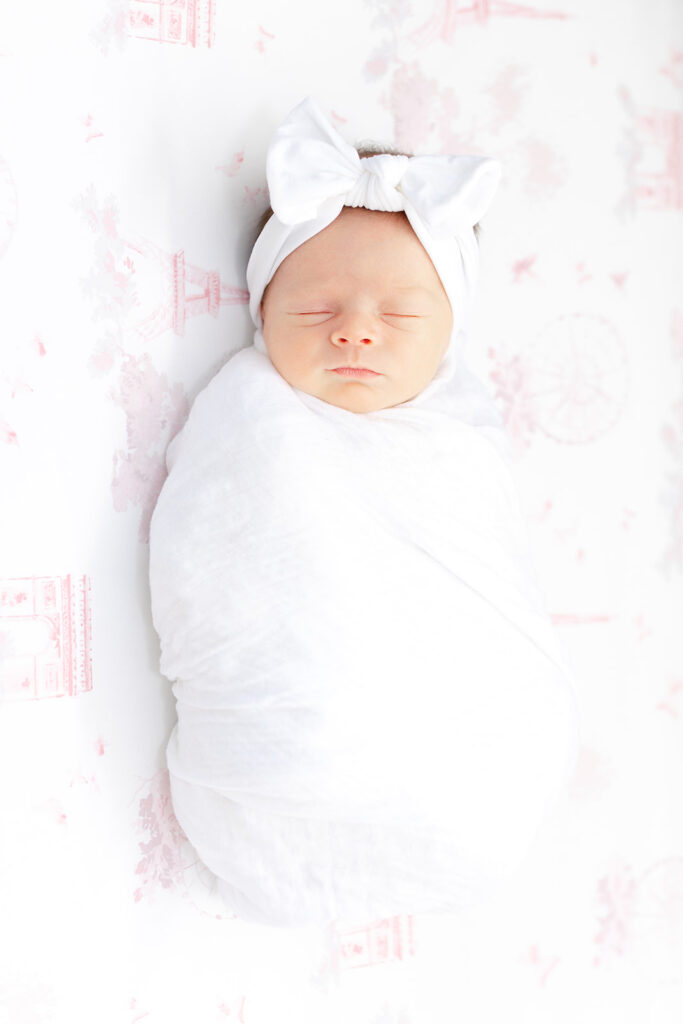 Baby wearing a headband sleeping in her crib