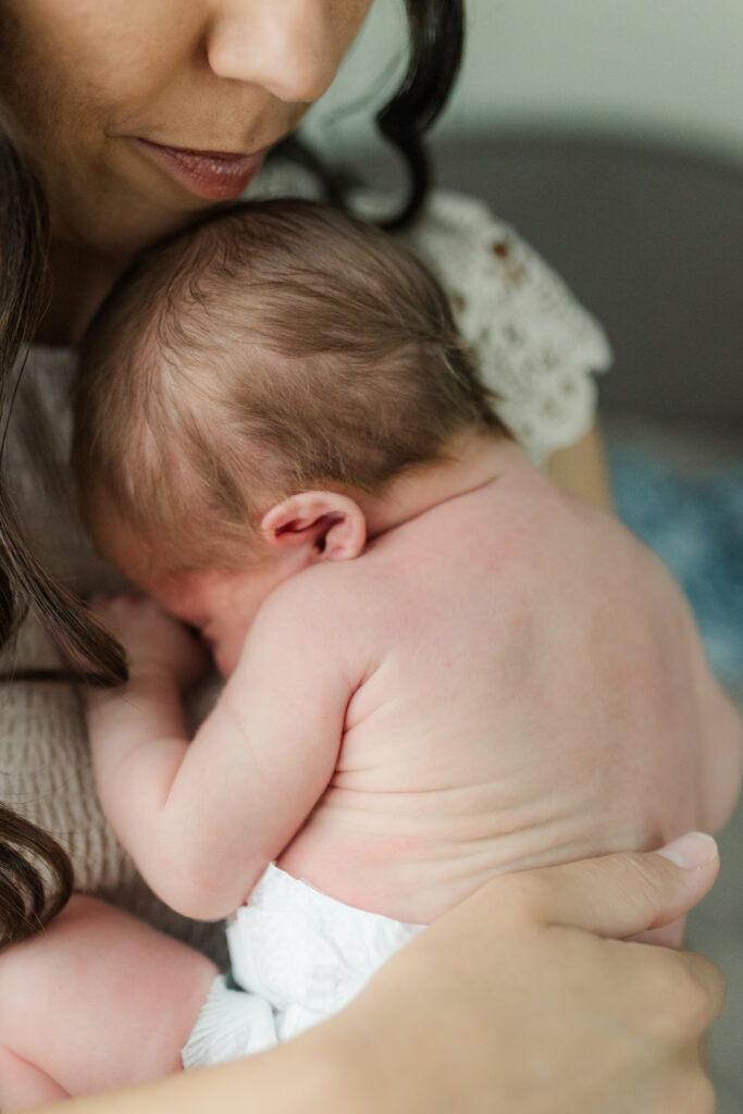 a mom holding her newborn baby with wrinkles on 
his back