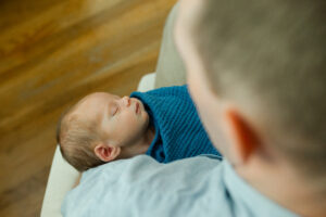 looking over the shoulder of a dad holding his baby boy 