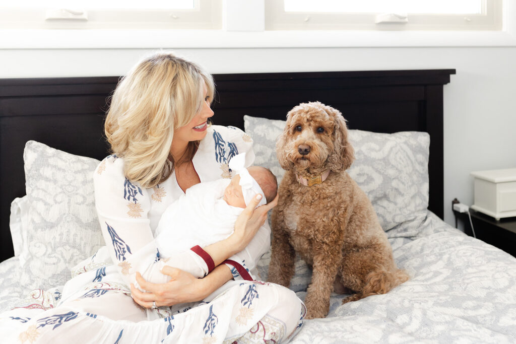 a mom holding baby while dog is close during a session with a newborn photographer in columbus, ohio