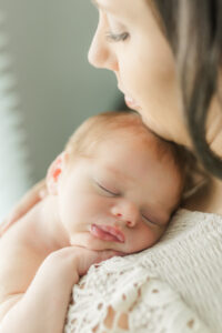 born baby sleeping on his mother's shoulder while his mother looks down at him