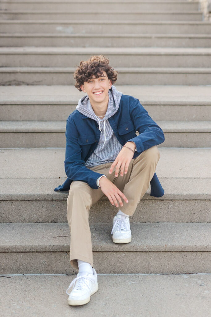 A senior guy sitting on steps at North Bank Park during his senior session.