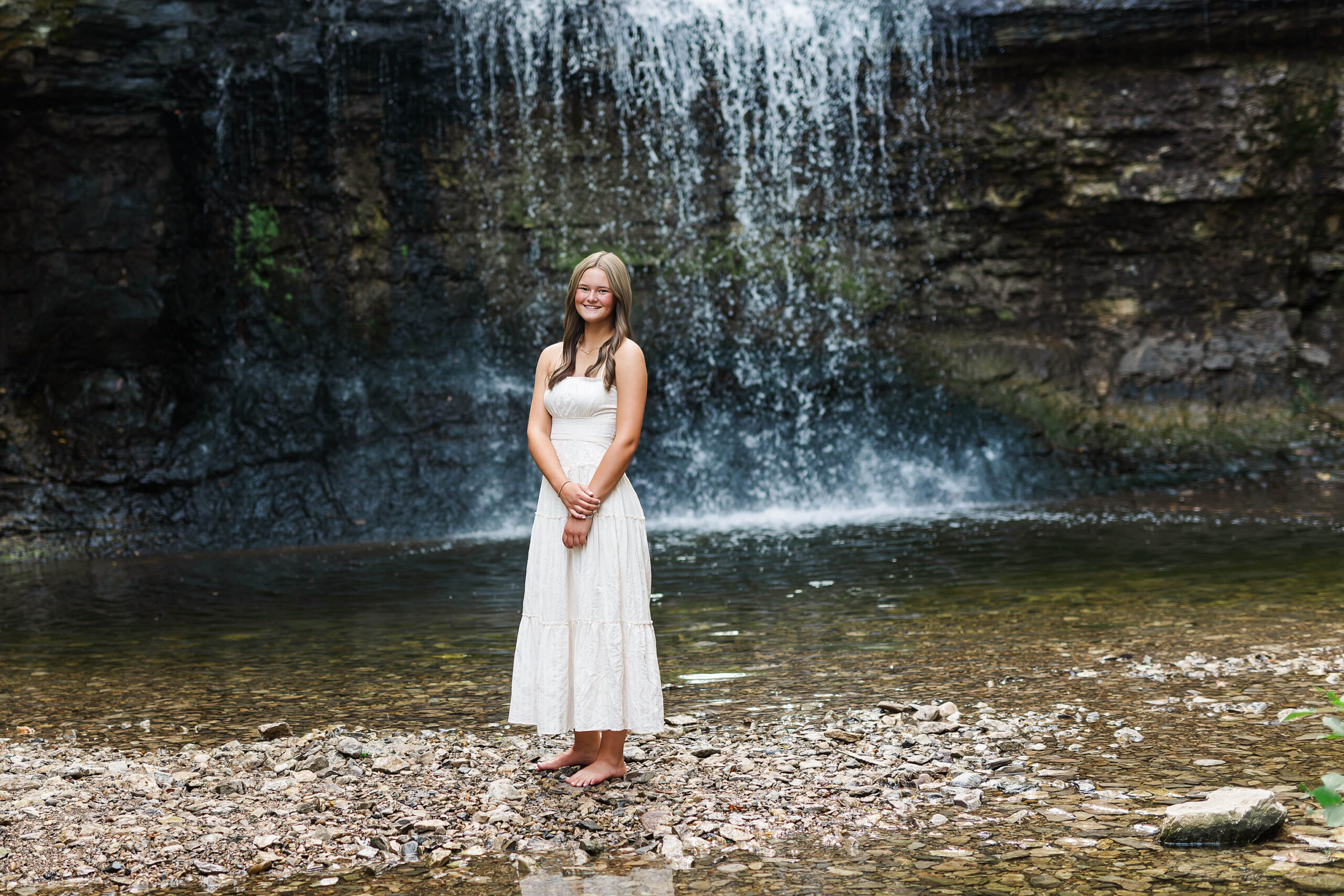 Senior standing by the waterfall at Quarry Trails.